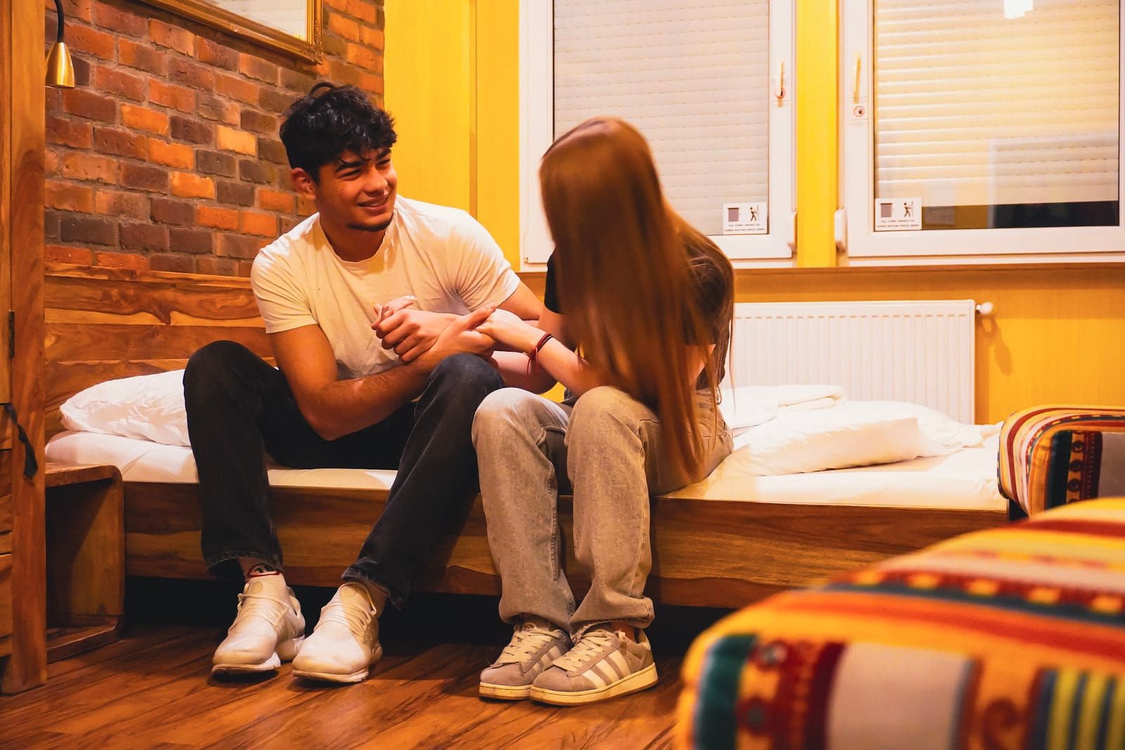 Two guests chatting on a dorm bed